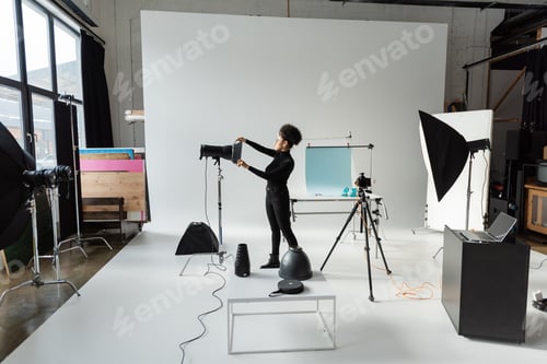 Preview: full length of african american content producer in black clothes assembling lighting equipment in
