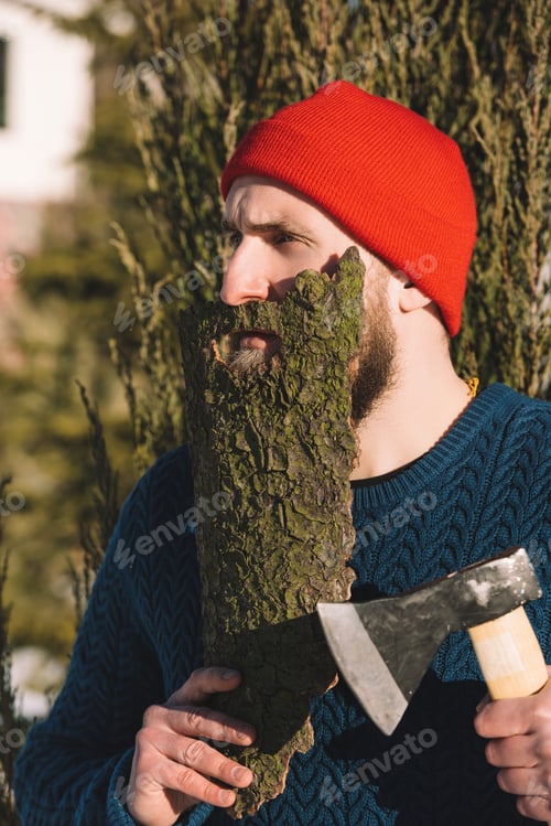 Preview: man with beard made of wood bark and axe in hand looking away outdoors