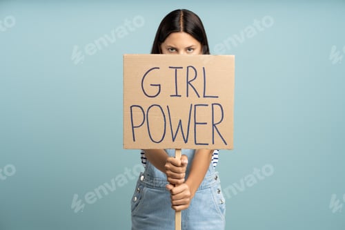 Preview: Teenage girl holding banner girl power slogan isolated on studio blue background