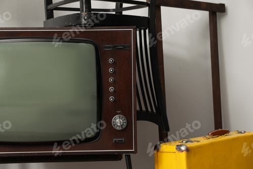 Vista previa: Retro TV, chairs and yellow suitacase near white wall. Used stuff