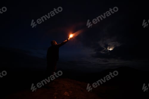 Preview: The male with a firework stick standing on the night mountain