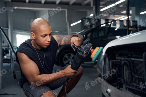 Preview: Auto-mechanic polishing car headlights with special attachment on grinder