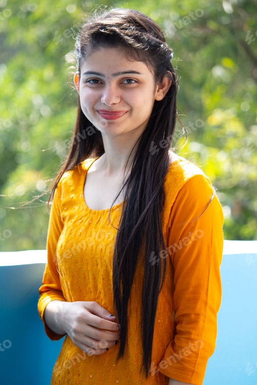 Preview: Vertical picture of a smiling lady in a yellow dress with long black hair.
