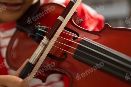Preview: Close-up of mixed-race schoolboy playing violin in classroom at elementary school