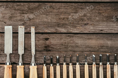 Preview: flat lay with wooden chisels for woodcraft on dark wooden tabletop