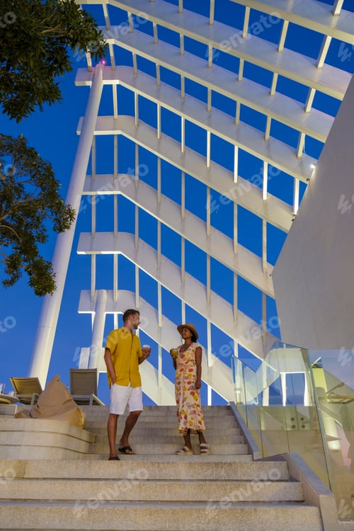 Preview: couple men and women having dinner during sunset at a rooftop restaurant looking out over the city