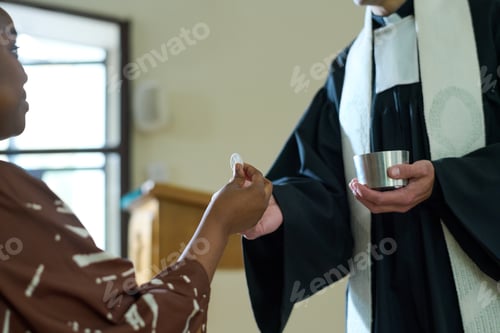 Preview: Young African American parishioner taking unleavened bread from hand of priest