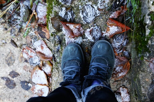 Preview: woman's feet standing on frosty leafs.