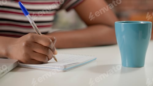 Preview: Female freelancer writing lesson information on notebook