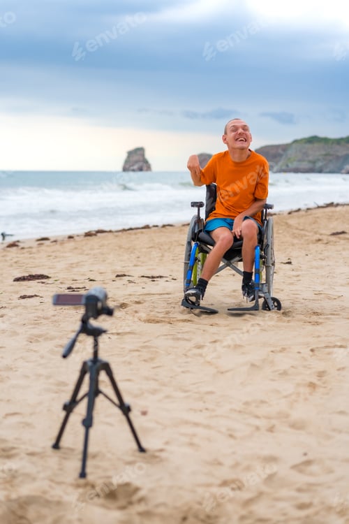 Preview: Portrait of a disabled person in a wheelchair on the beach recording a video