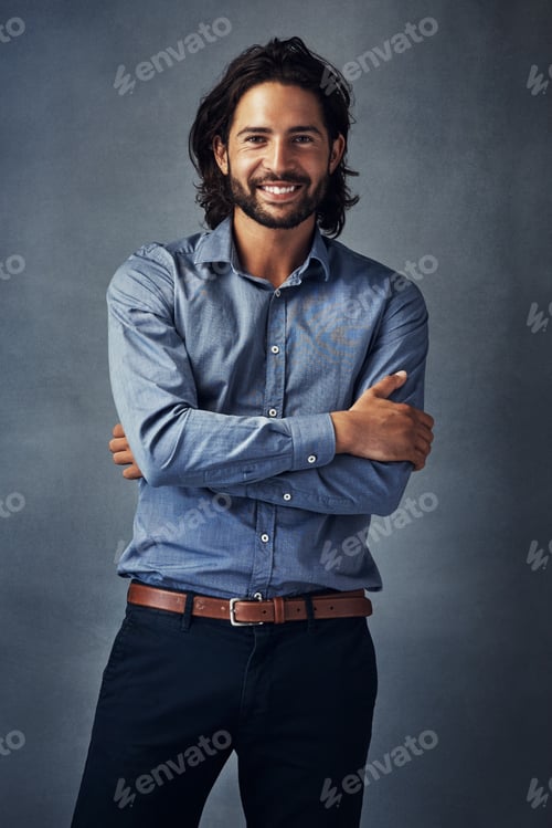 Preview: Studio portrait of a handsome young man standing with his arms folded against a grey background