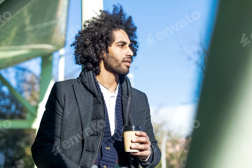 Preview: man with beard smiling positive standing at the street drinking a take away cup of coffee