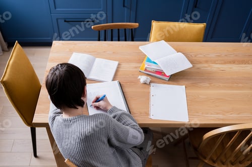 Preview: Unhappy teenager boy doing school lessons at home. Problems and difficulties of home education