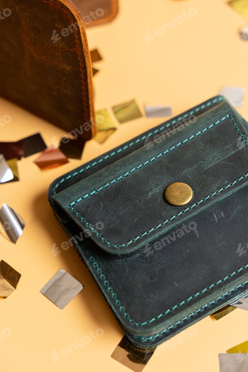 Preview: purse with a pile of confetti is depicted on table. wallet is made of leather and decorated.