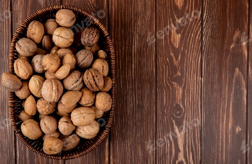 Preview: top view of whole walnuts in a wicker basket on wooden background with copy space