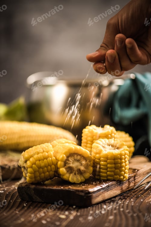 Preview: Hand salting hot cooked corn on the cob