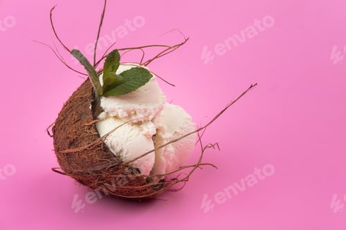Preview: Vanilla ice cream balls in an empty coconut decorated with mint leaves on a pink background