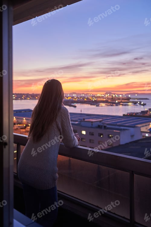Preview: Young woman contemplating the sea from a balcony