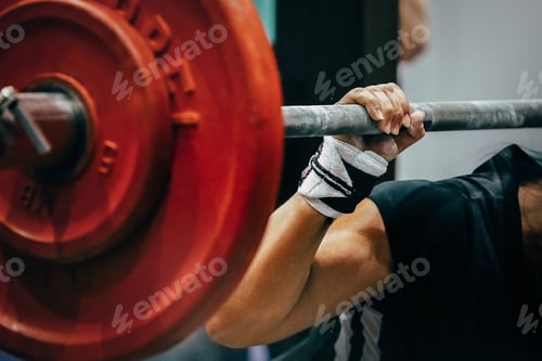 Preview: close-up red plates barbell and arm female powerlifter during squat