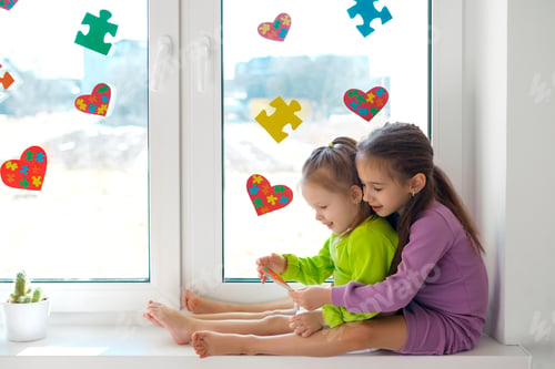 Preview: Girl gave her little sister a heart-shaped card with puzzles for autism Day.