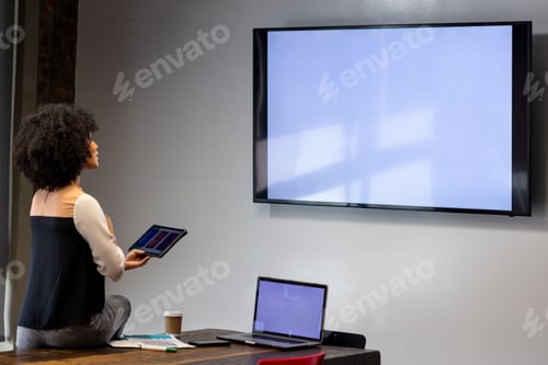 Preview: African american businesswoman with digital tablet having video call on tv with copy space at office