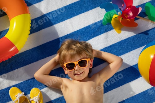 Preview: Smiling Child Relaxing on Beach Towel in Sunlight