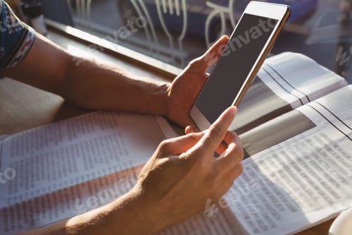 Preview: Cropped hands of man with newspaper holding tablet in cafe