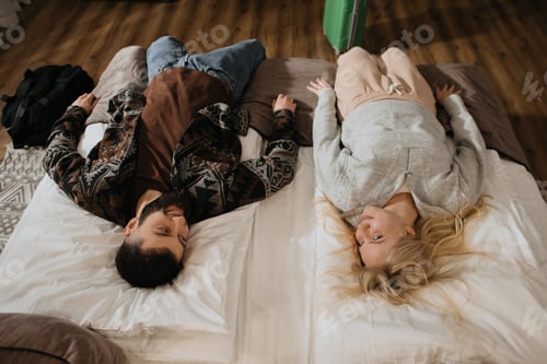Preview: Happy couple relaxing on beds in hotel
