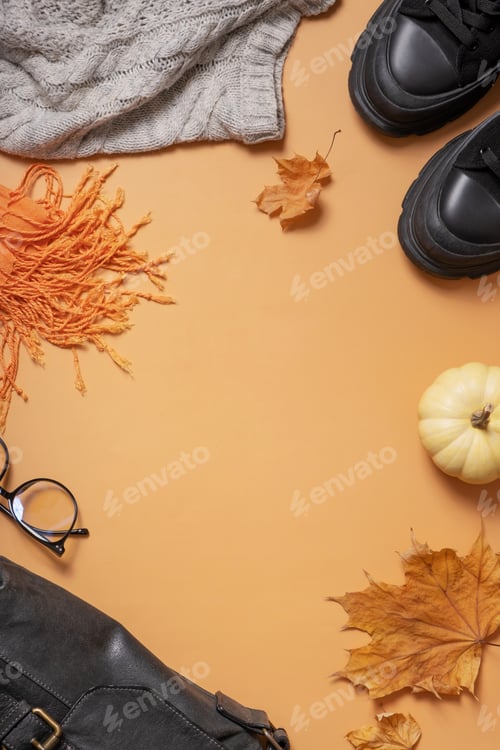 Preview: Woman's black shoes with autumn leaves and pumpkin on coloured background top view, flat lay