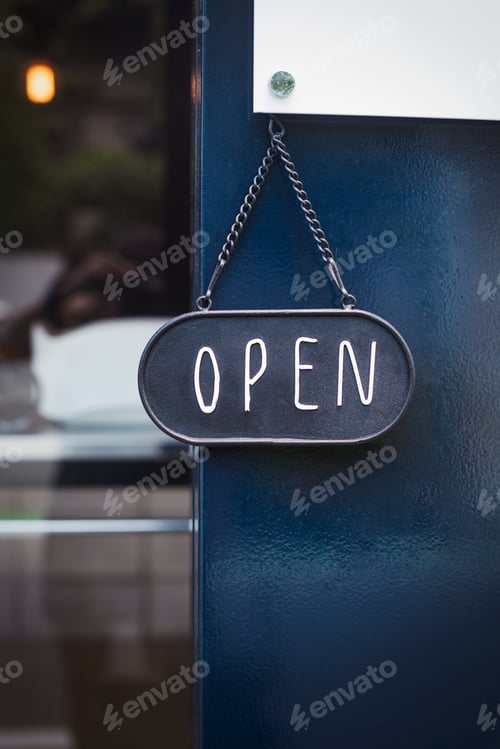 Preview: Close up of open sign on glass door to a bakery.