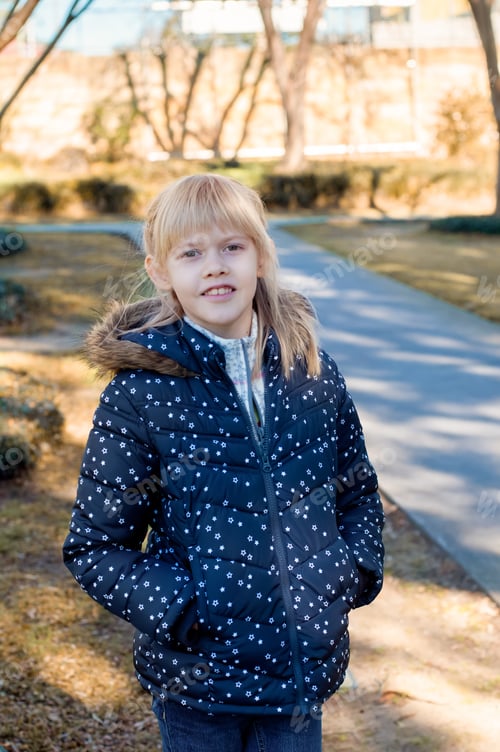 Preview: Cute Caucasian girl wearing warm coat in the autumn park