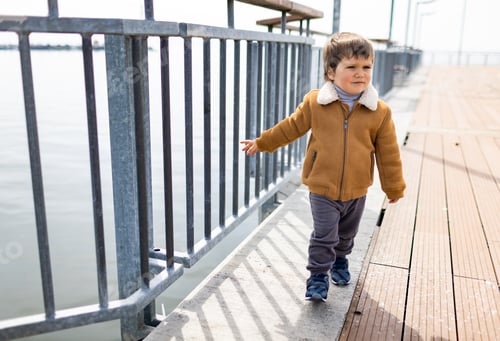 Preview: A boy in warm clothes walks along the pier with a fence near the Black Sea