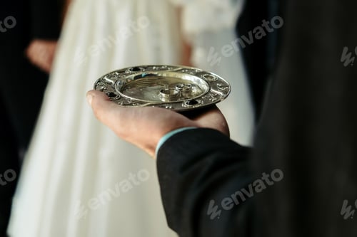Preview: blonde bride and happy groom, putting on rings in the old church