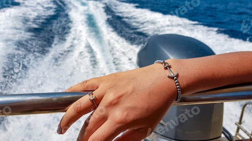 Preview: Close-up of woman's hand on boat Wearing luxury nautical themed jewelry.