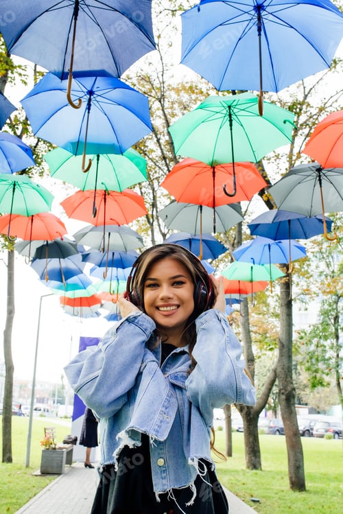 Preview: beautiful and smiling girl with headphones looking at camera.