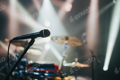 Preview: Close shot of a microphone standing on a stage with a drum kit in the background