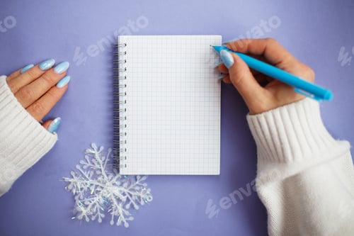 Preview: Woman hand with winter nails holding pen on notebook and writing wish list