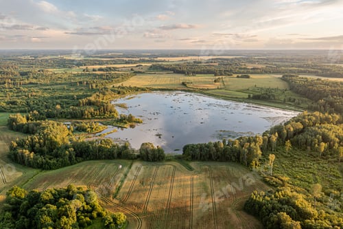 Preview: Vast landscape with tranquil lake surrounded by lush greenery and farmland at sunset