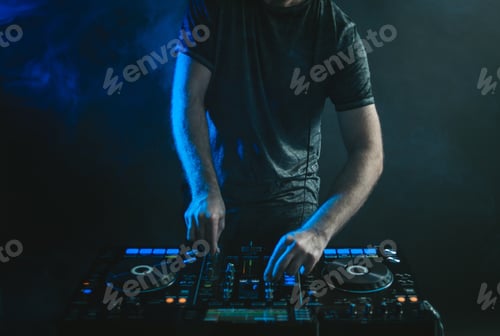 Preview: Male DJ working under the lights and smoke against a dark background in a studio
