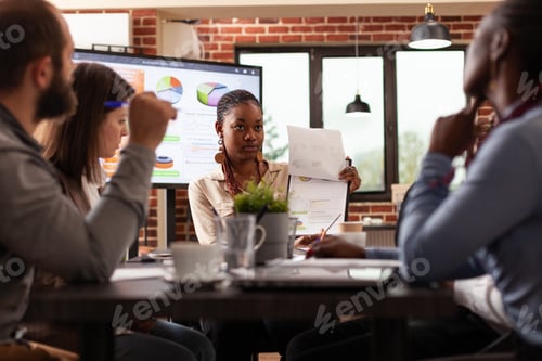 Preview: Businesspeople sitting at meeting table discussing management strategy