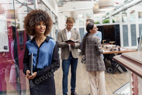 Preview: Smiling african businesswoman standing in modern office on colleagues background