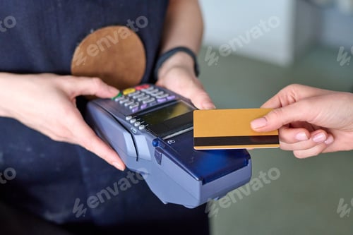 Preview: Hands of shop assistant holding card reader during contactless payment