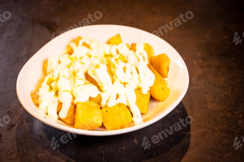 Preview: Bravas with aioli sauce on a black background, on a blue plate