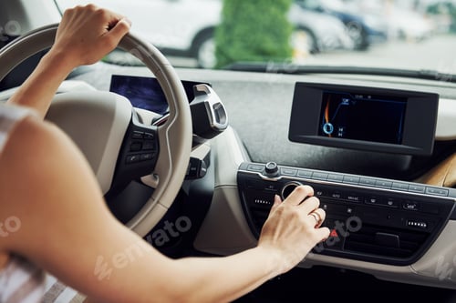Preview: Turns the knob. Female driver inside of modern automobile. Testing brand new car