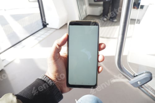 Preview: young man hand using smart phone with empty screen inside of metro train