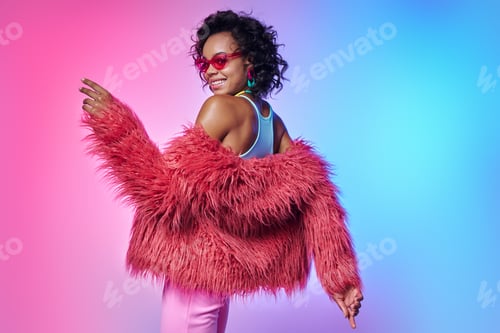 Preview: Attractive African woman in trendy clothes dancing against colorful background