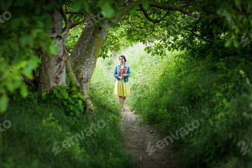 Preview: Woman in yellow dress gathering poppy and wildflowers, walking in summer meadow