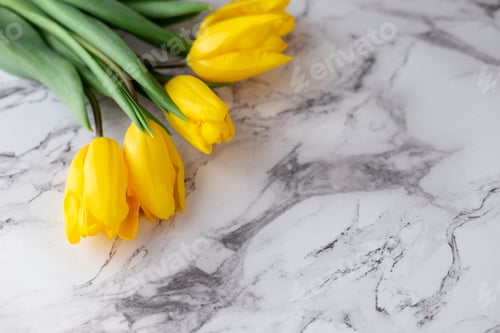 Preview: A bouquet of yellow tulips lies in the upper left corner on a granite