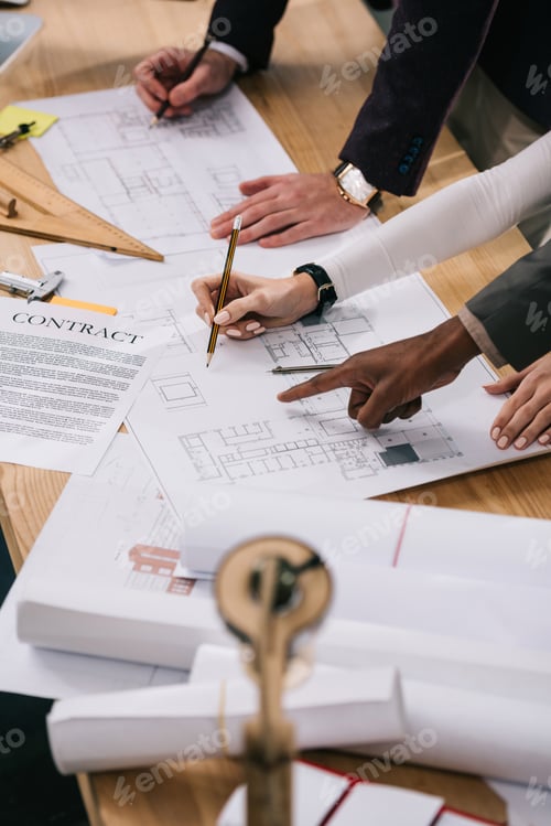 Preview: cropped view of multiethnic architects discussing documents and drawing blueprints in office