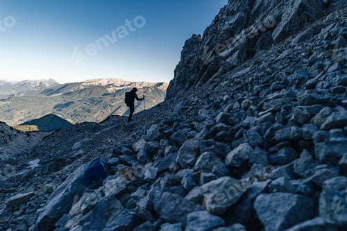 Preview: Low angle shot of an adventurous person hiking a mountain full of rocks in Totes Gebirge, Austria
